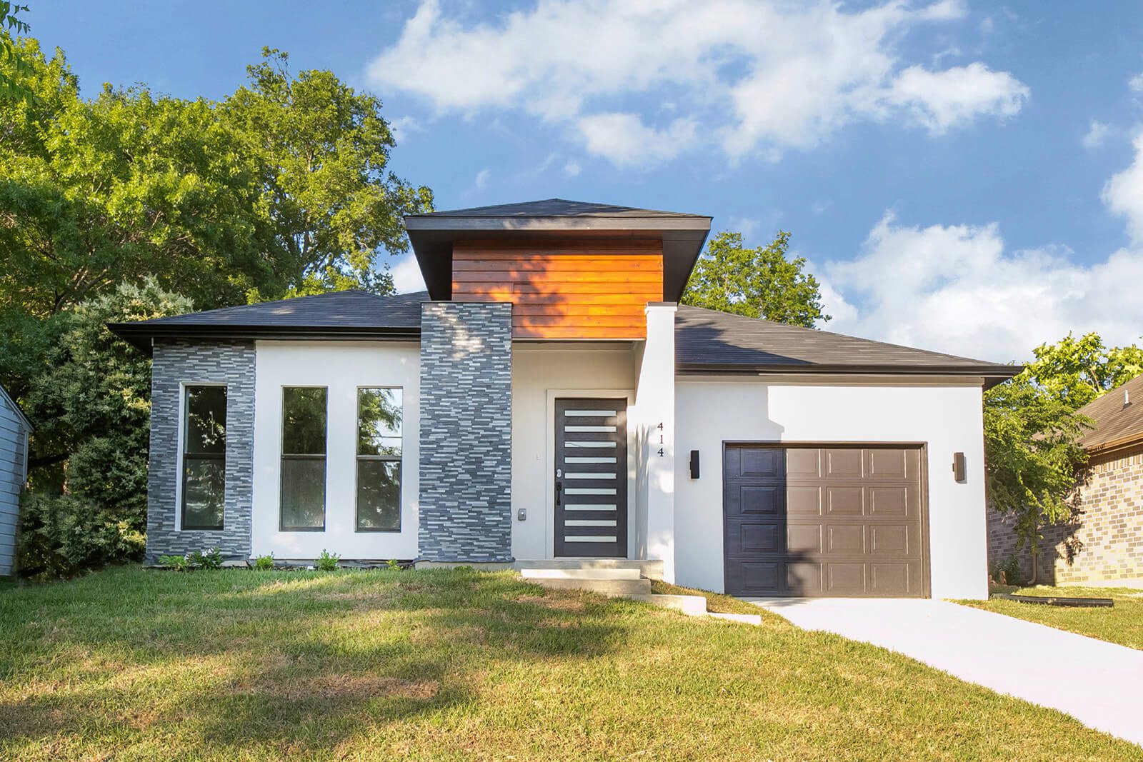 414 Avenue E, a white house with stacked stone columns and a cedar clad entry gable