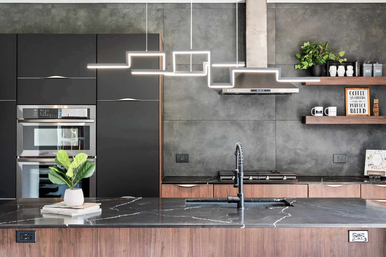 A Memar Interiors kitchen with walnut cabinetry, a black stone island and a linear pendant light