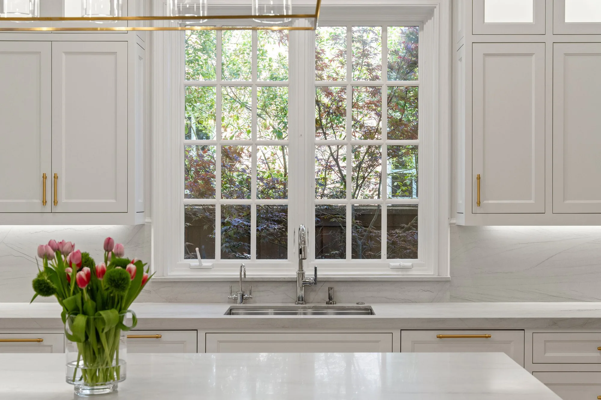 University Park Home, a white kitchen with marble counters, brass hardware and a garden window